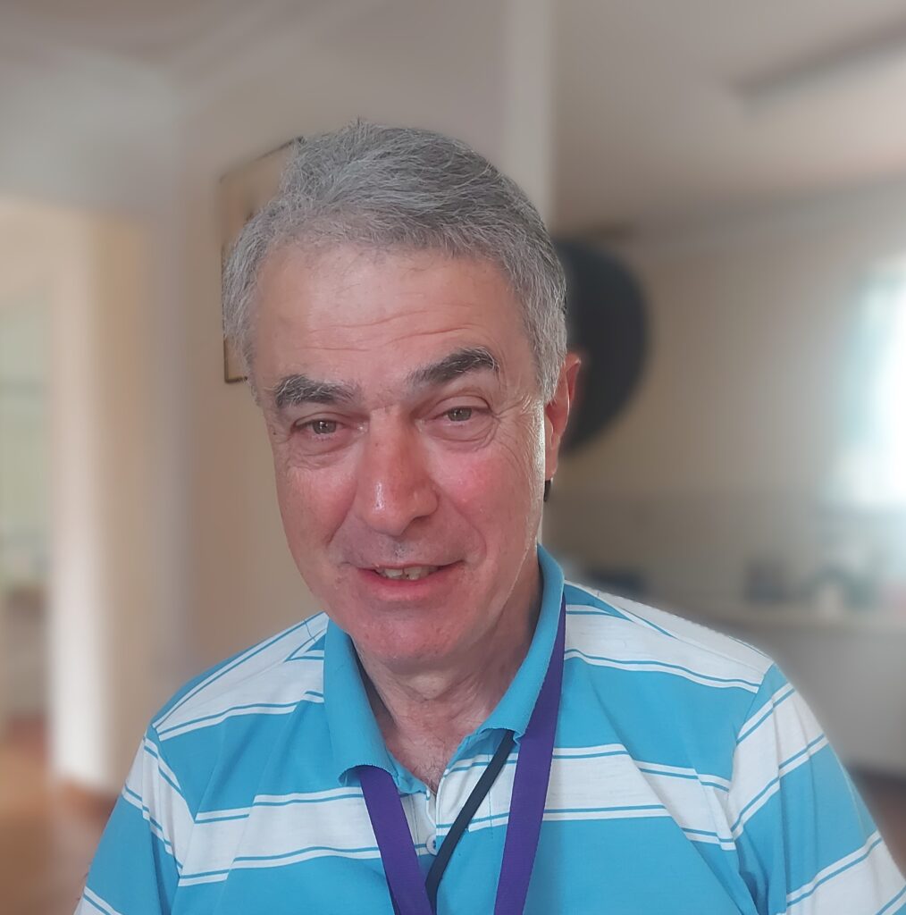 Enzo Moscufo, board member profile picture. Enzo has short grey hair and is wearing a blue and white striped top.