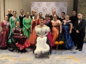 A group of people in bright colourful outfits, some standing, some in wheelchairs, with medals around their necks. 